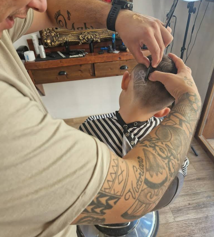 Barbero de Kings Barber perfilando un corte con maquinilla en plena faena.